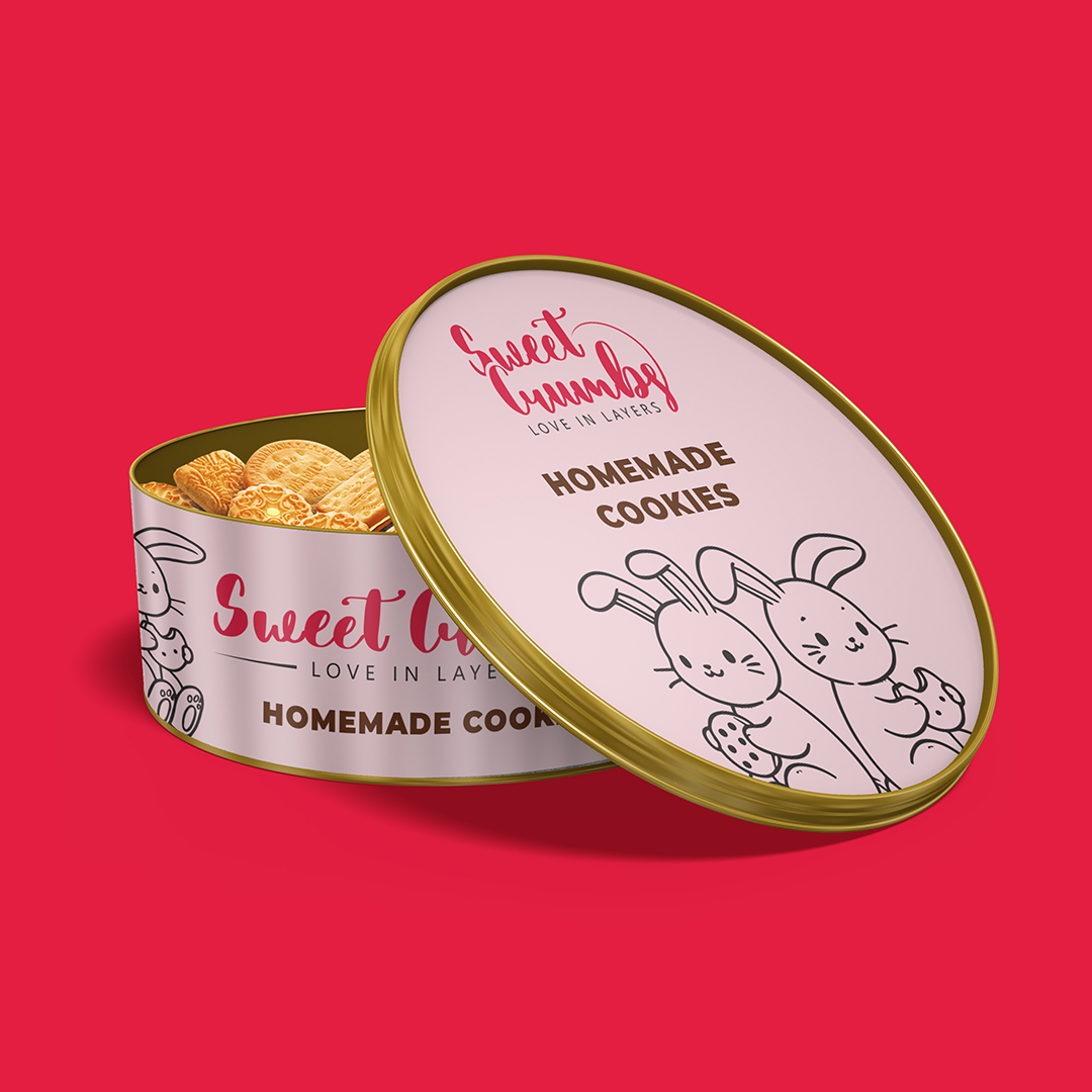 Round container with cookies and a lid featuring bunny illustrations and text, set against a red background.