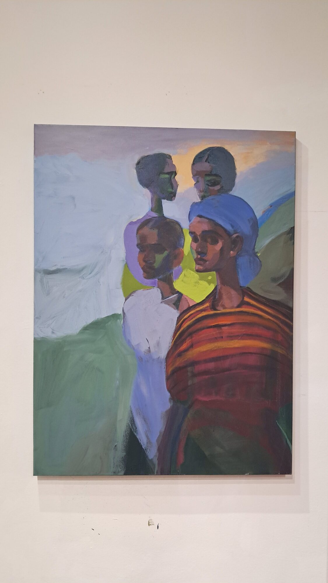 Four children with dark skin and short hair, standing outdoors, wearing colorful clothing, with a light background.