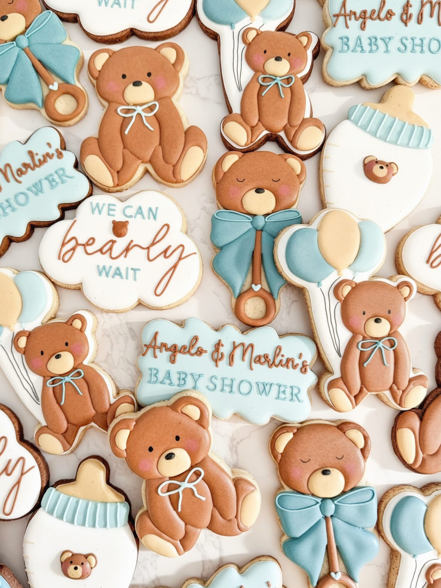 Collection of baby shower cookies with teddy bears, clouds, and baby bottles, decorated in pastel colors.