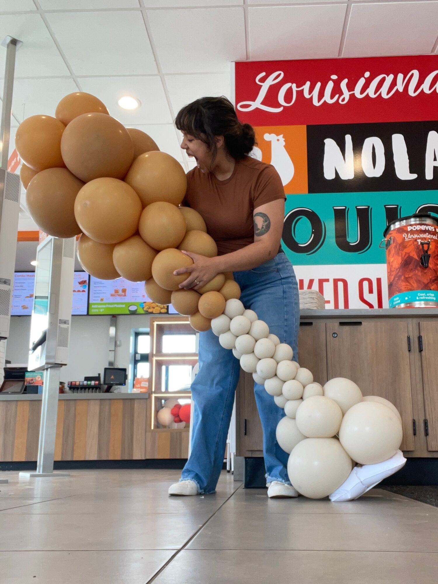 Person arranging balloon sculpture resembling a large animal with a long tail in an indoor space.