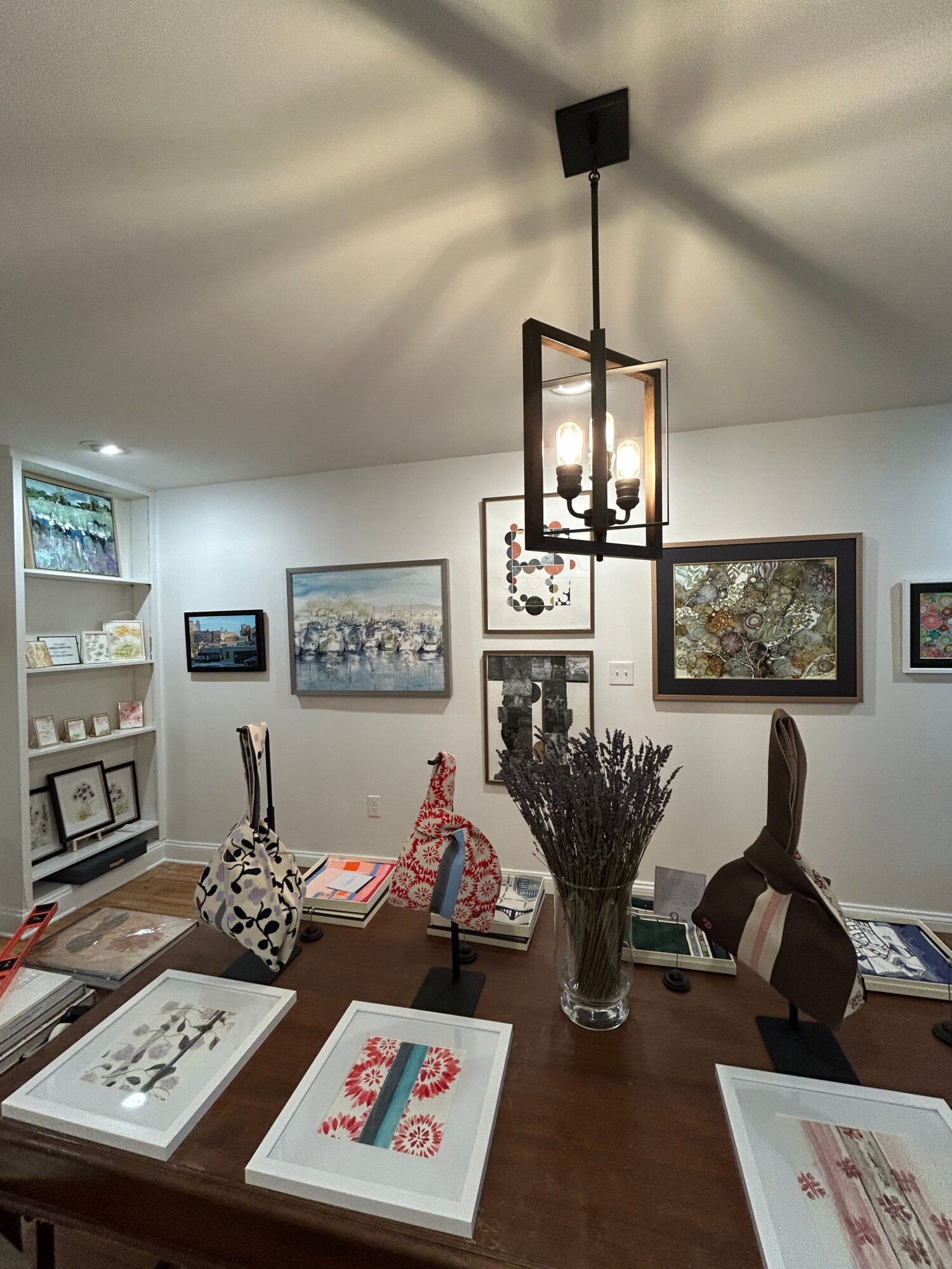 Dining table with decorative items, books, and framed pictures on the wall, illuminated by a modern ceiling light fixture.