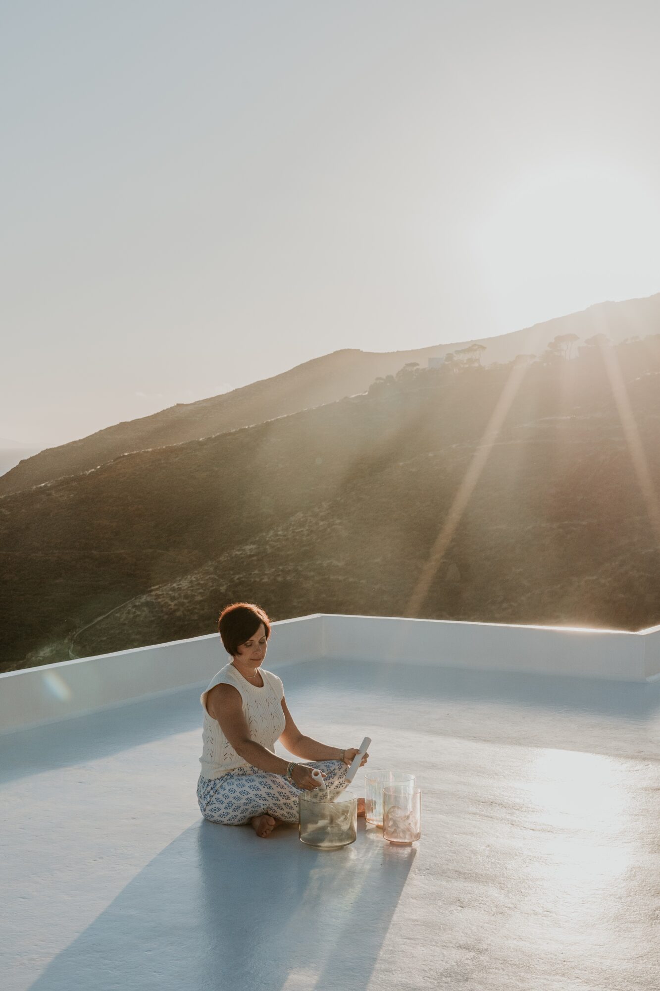Child sitting in a shallow pool with a mountain and bright sky in the background.