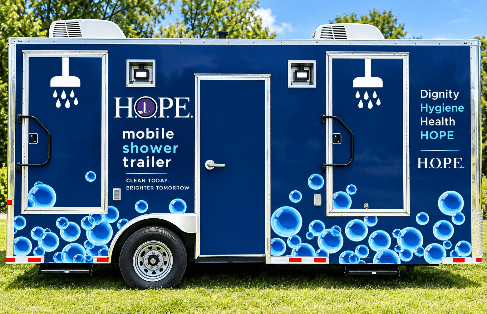 Mobile shower trailer with blue design, water bubbles, and text promoting hygiene and dignity, set outdoors with trees and sky.