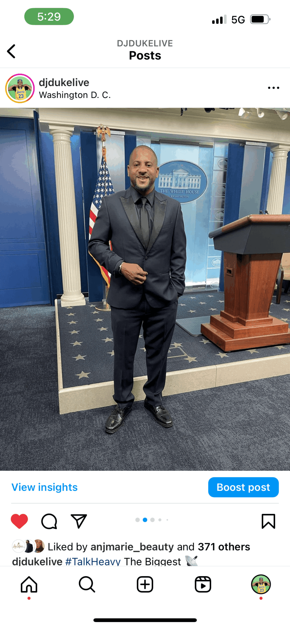 Man in a suit standing in front of a podium with the U.S. Capitol in the background, indoors.
