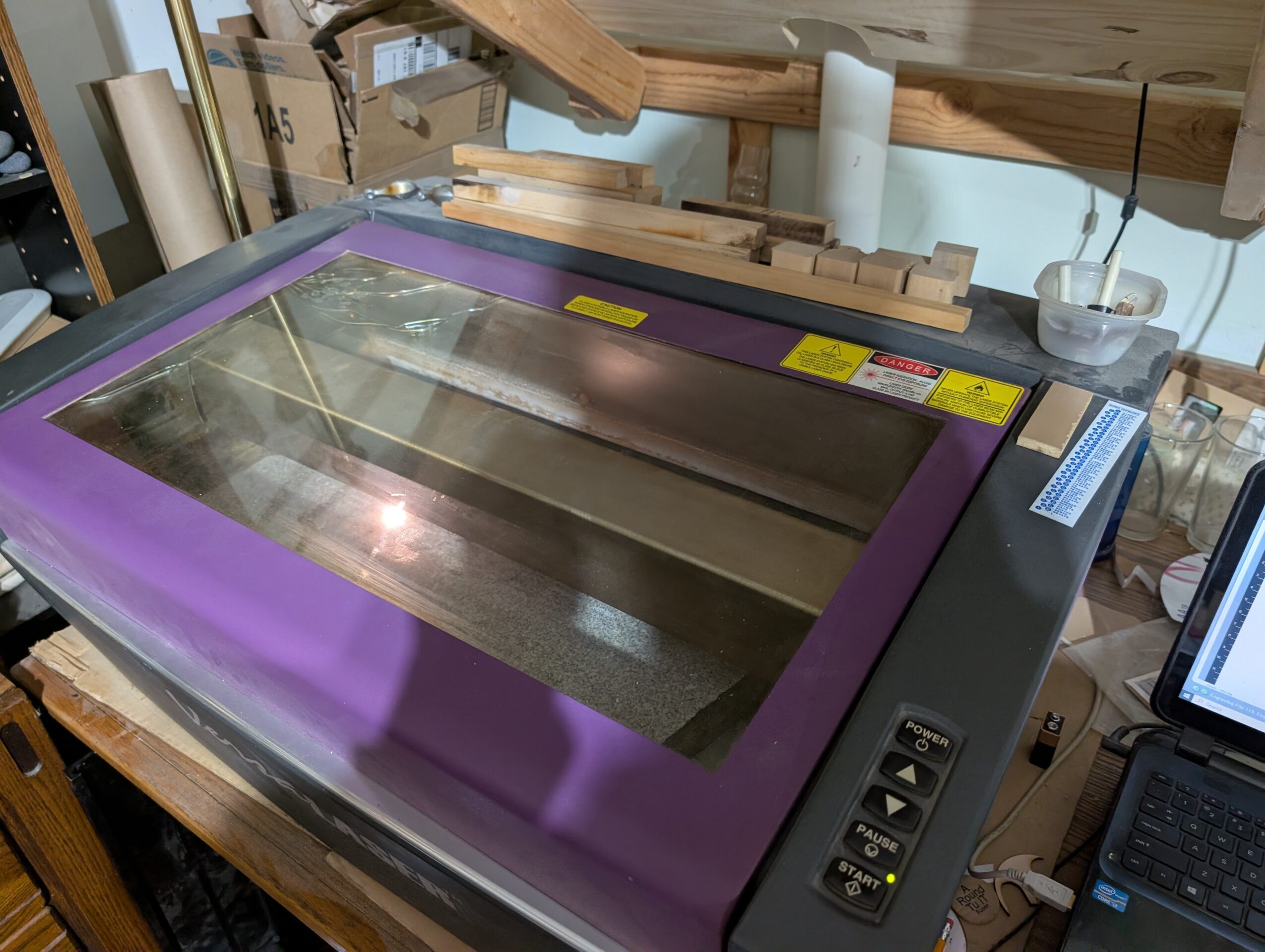 Large machine with a glass top and purple border, situated on a wooden workbench in a workshop.