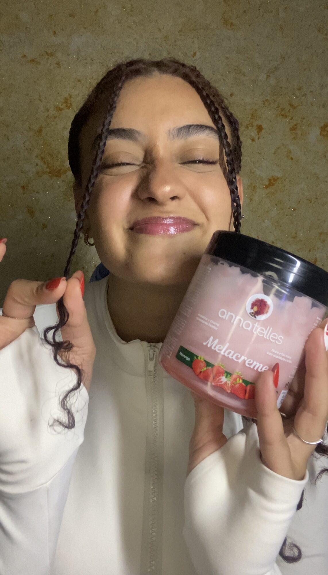 Smiling woman holding a container of strawberry-flavored product, eyes closed, against a textured background.