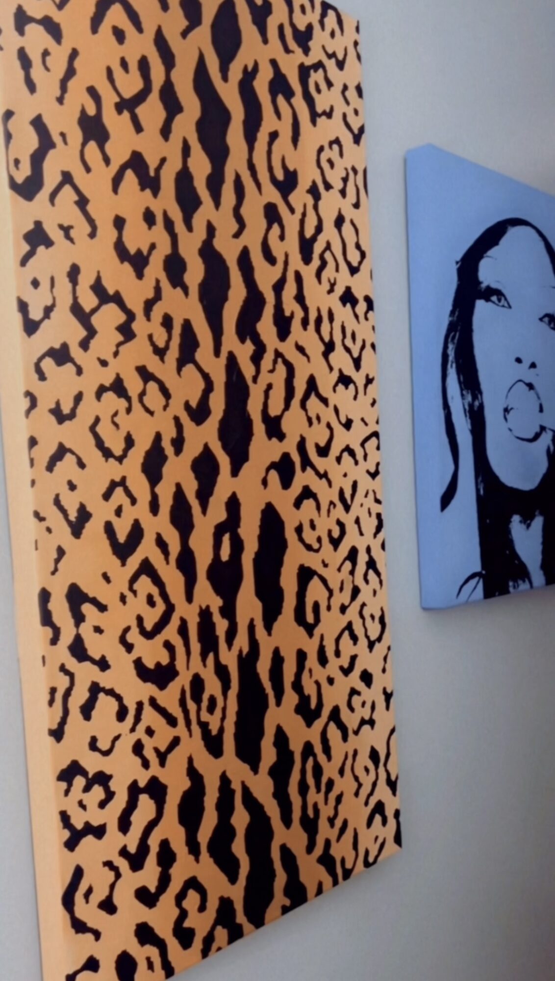 Leopard print pattern on a vertical surface next to a blue canvas with a black and white portrait of a woman.