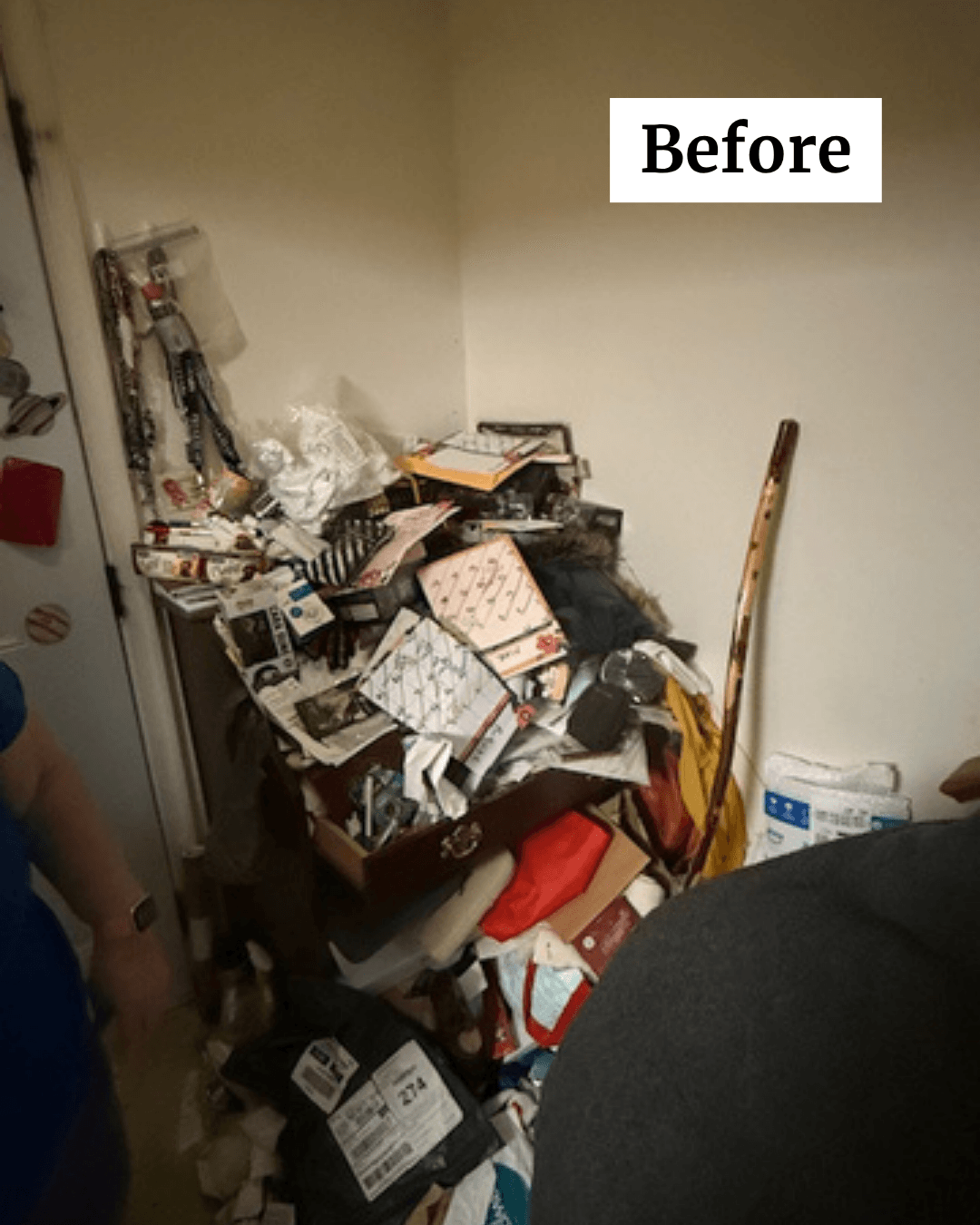 Cluttered corner with a small table piled with papers, books, and miscellaneous items, next to a wall and a chair.