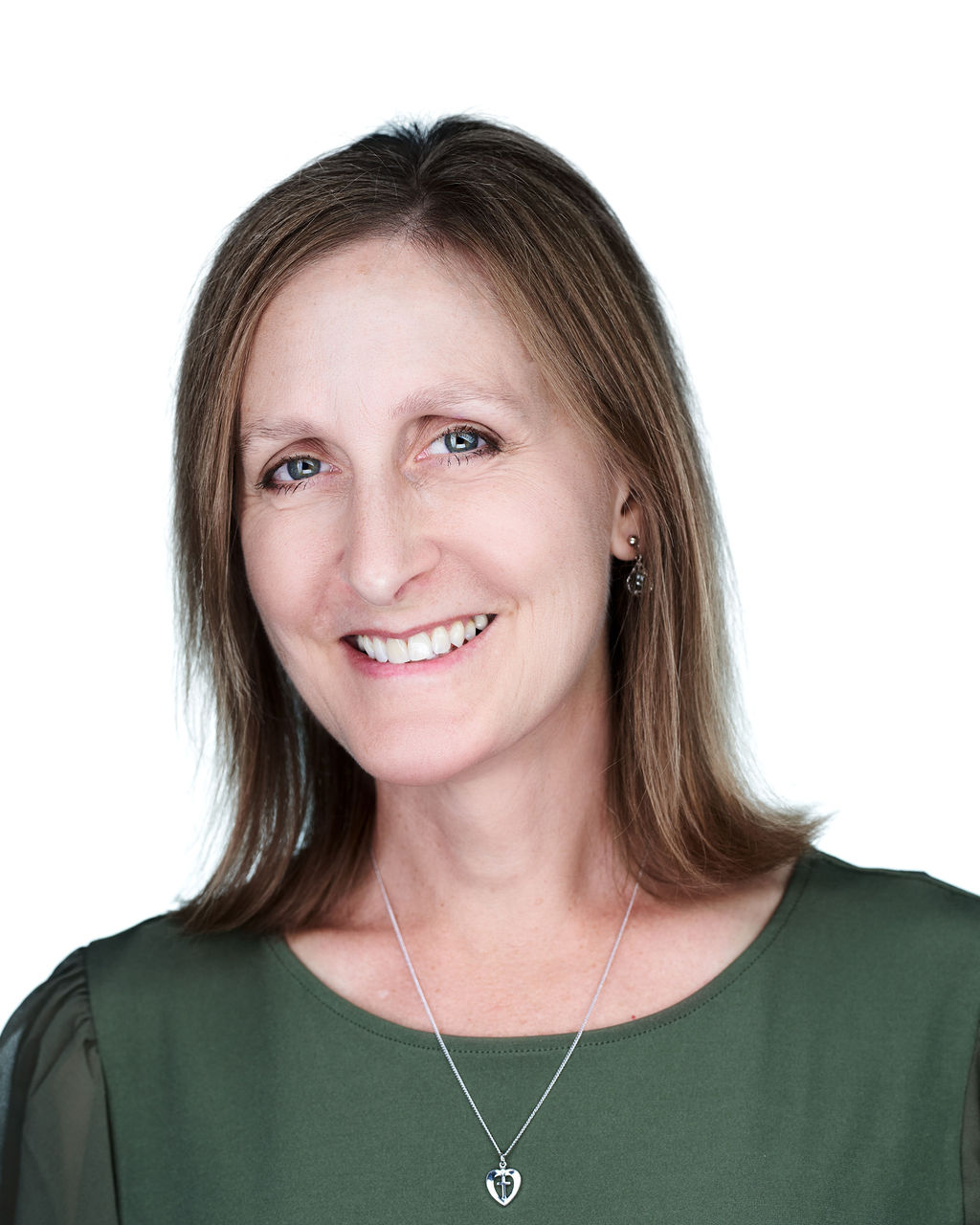 Woman with shoulder-length brown hair smiling, wearing a green top and a necklace, against a white background.