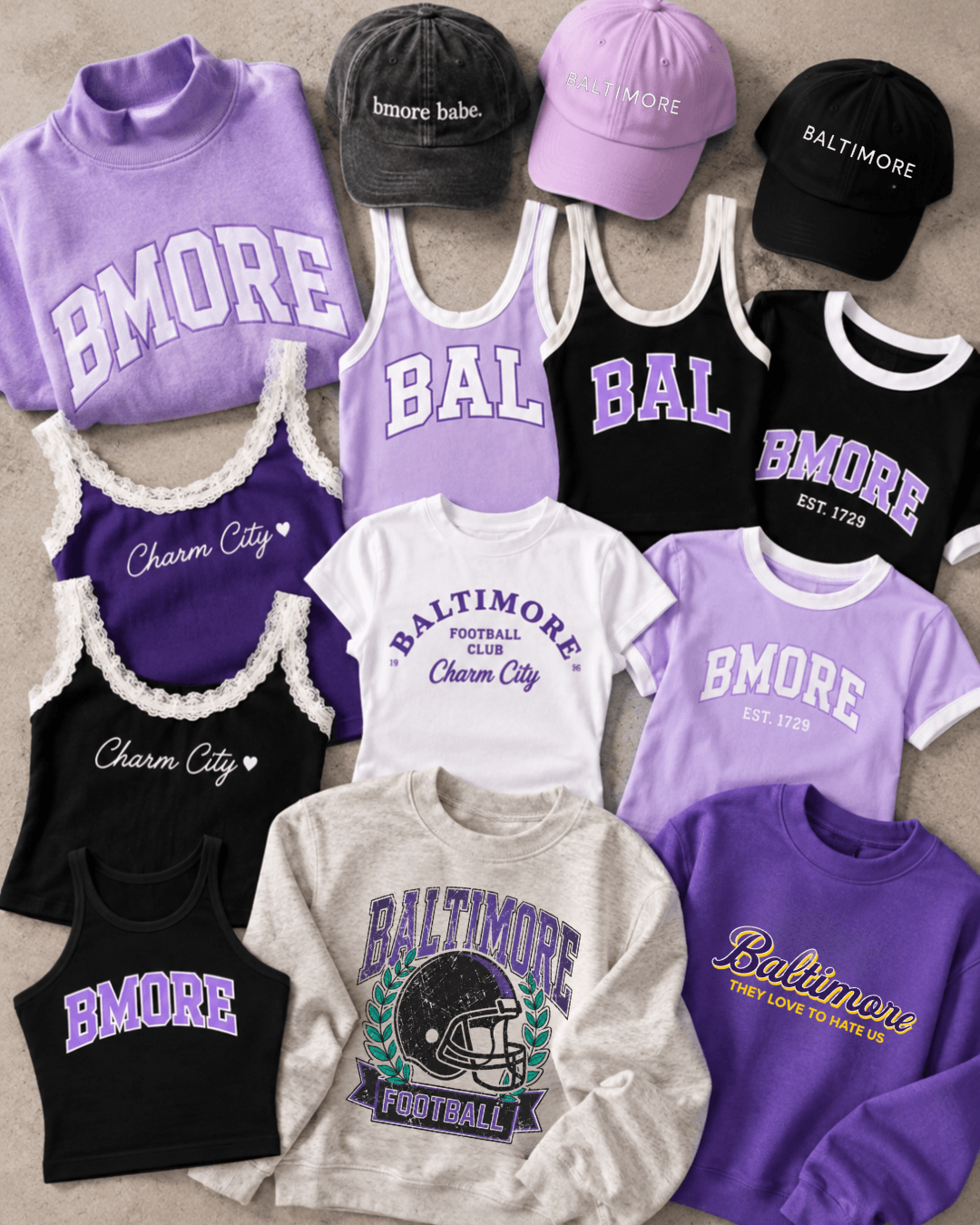 Collection of Baltimore Ravens-themed clothing and hats, including sweatshirts, t-shirts, and caps in purple, black, gray, and white colors.
