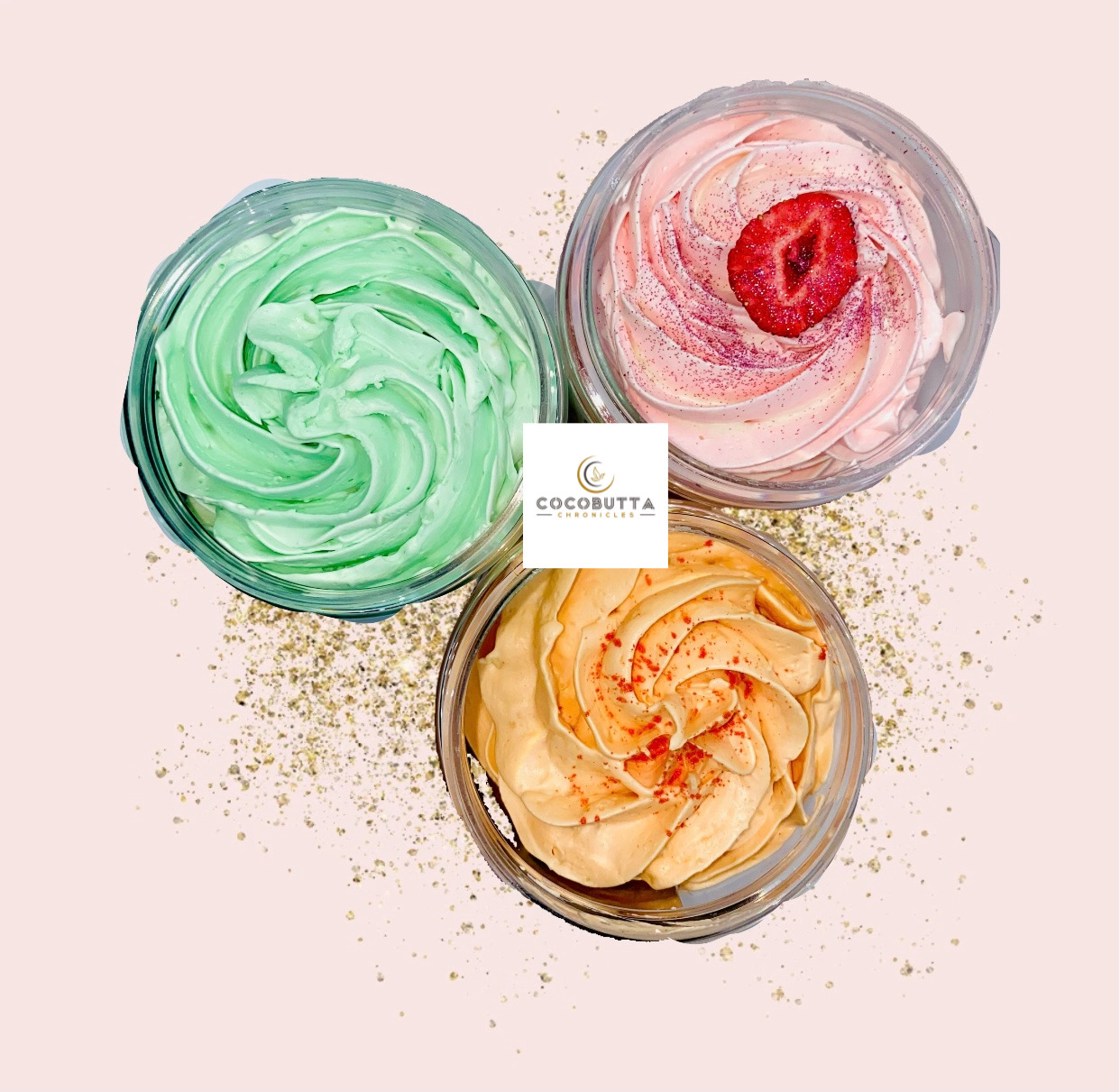 Three bowls of colorful whipped creams or frosting with sprinkles on a light pink background.