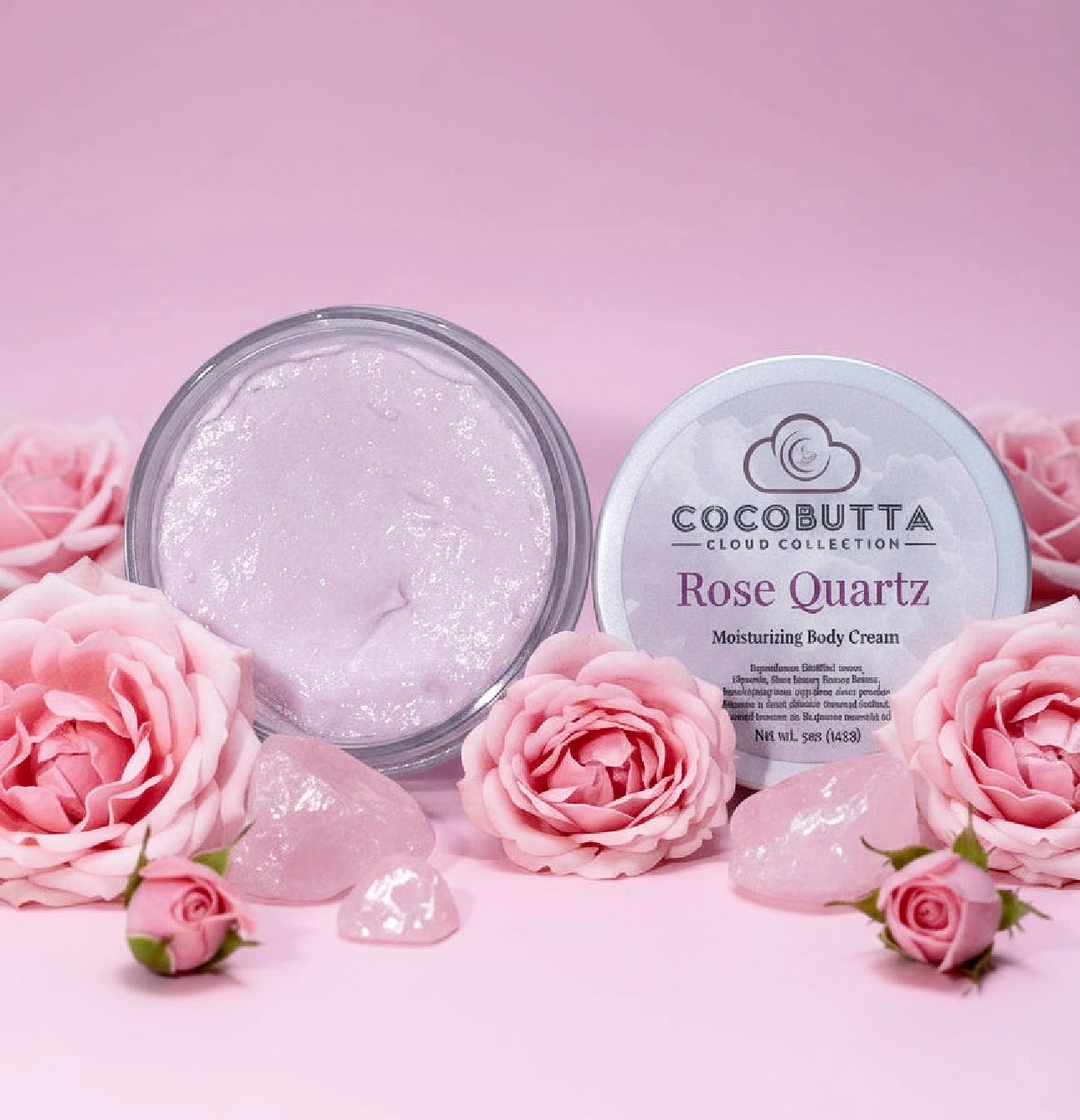 Open jar of pink body cream surrounded by pink roses on pink background.