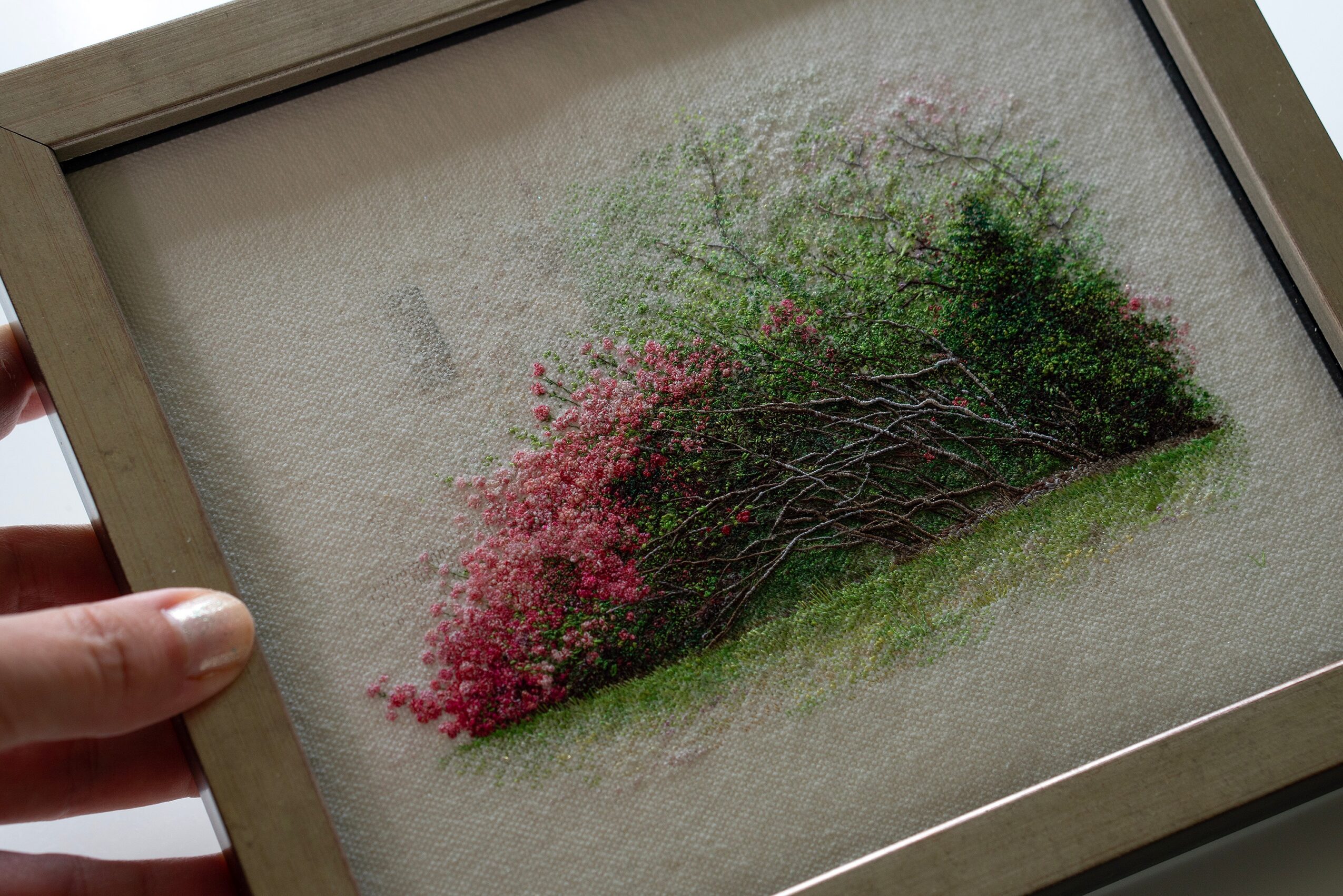 Framed embroidered artwork of a pink and green bush on a beige background.
