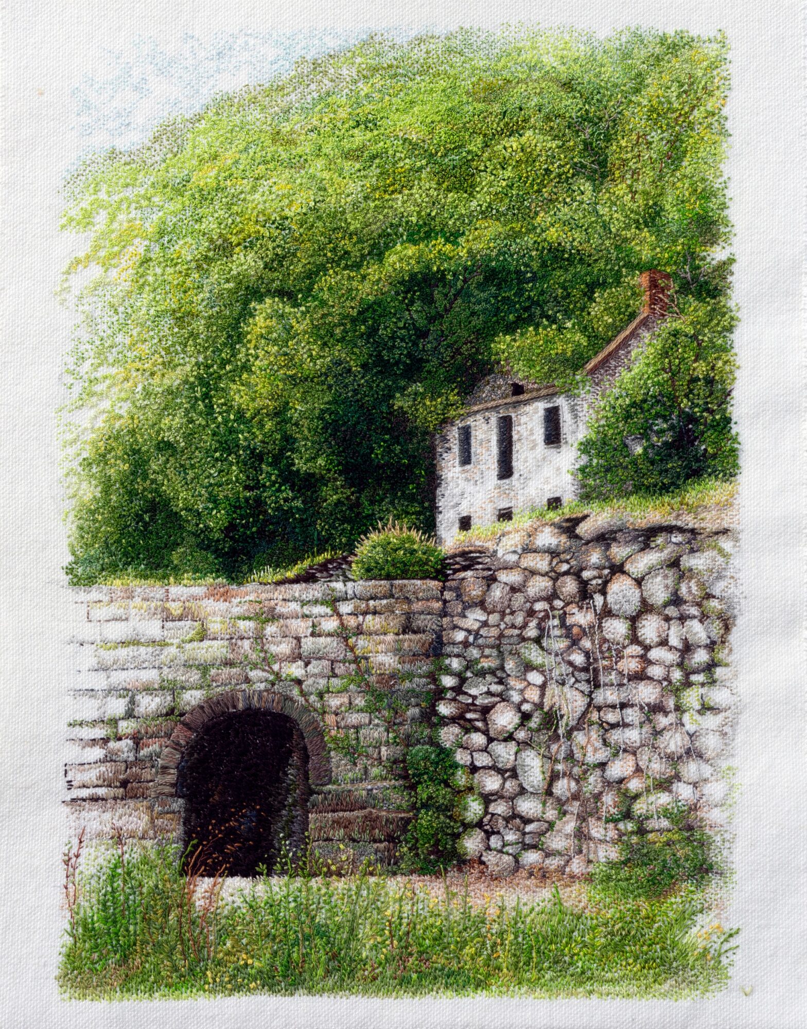 A stone bridge with an arch, a white house with a red roof, surrounded by green trees and grass.