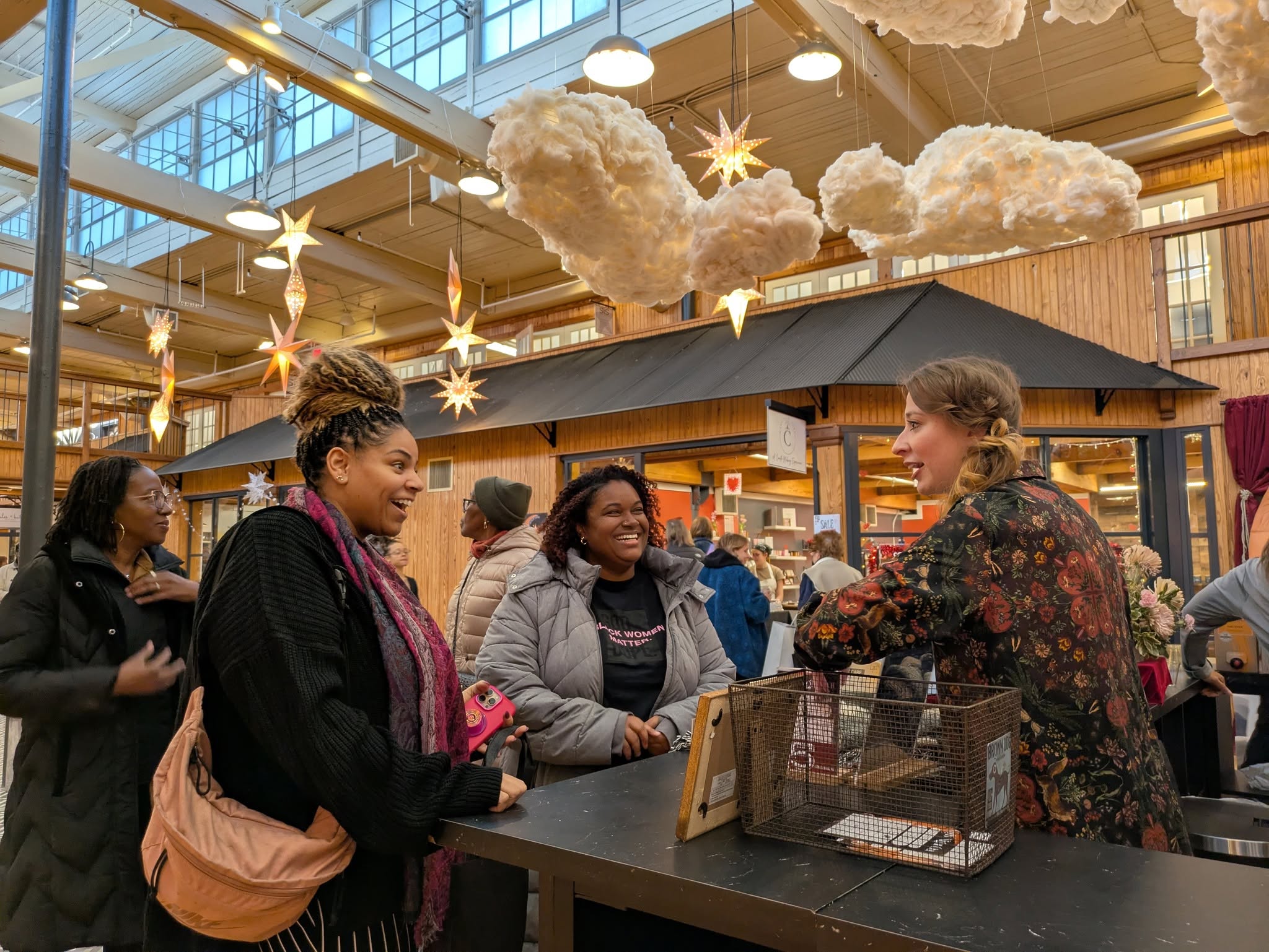 Group of people talking at a counter inside a decorated indoor space with clouds and star decorations hanging from the ceiling.