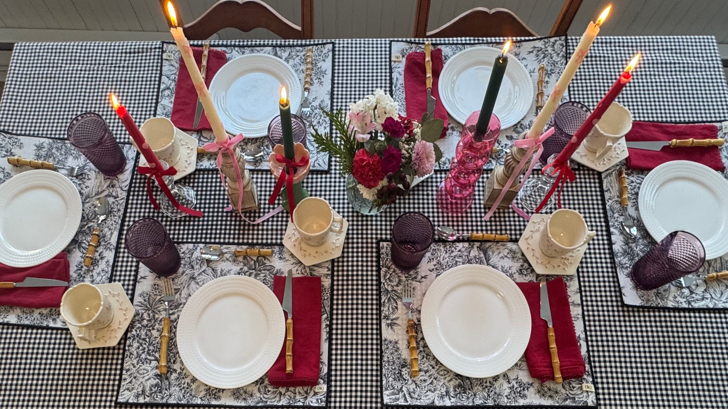 Table setting with plates, napkins, candles, and floral centerpiece, viewed from above.