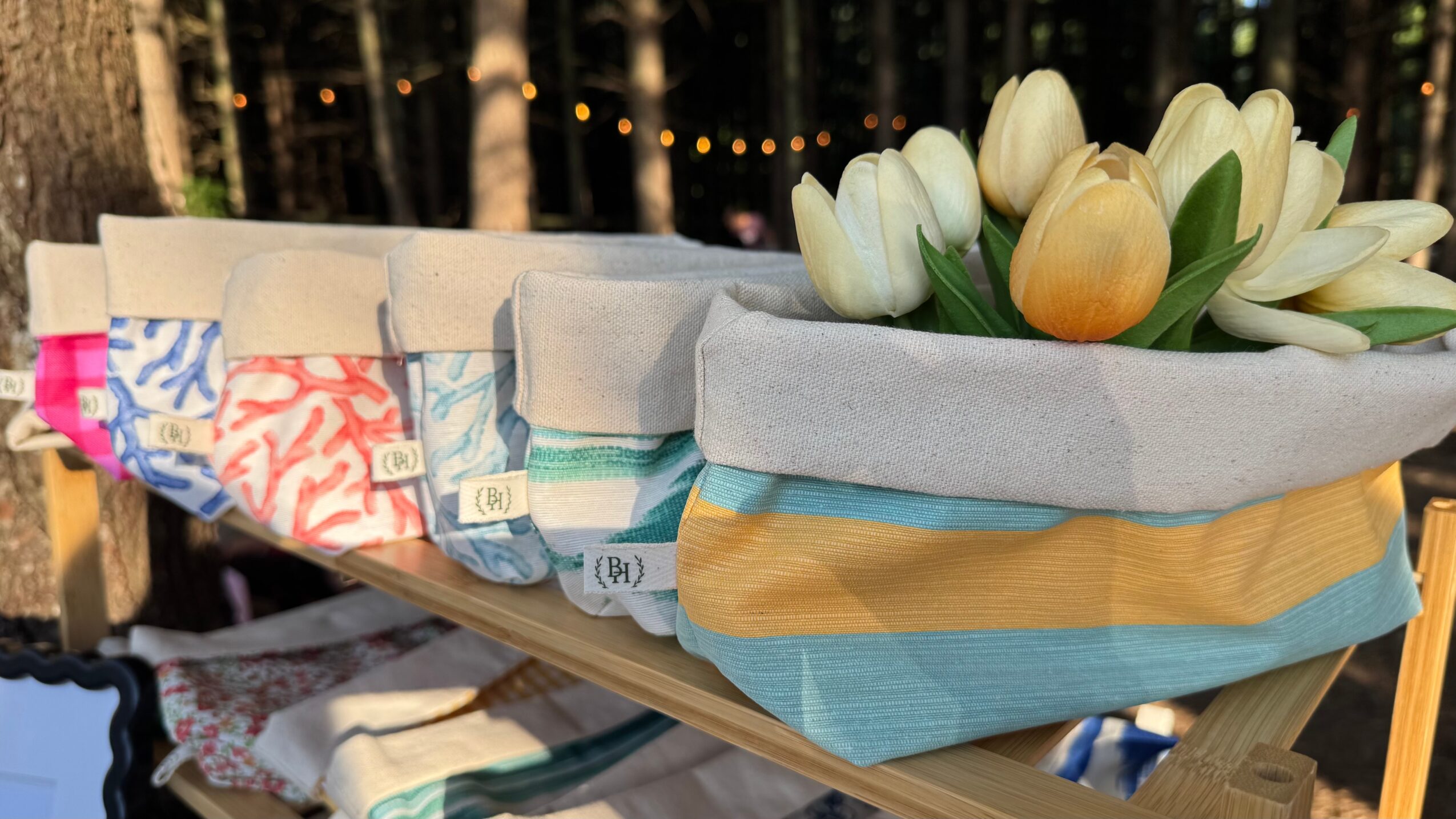 White tulips in a fabric-lined basket outdoors with string lights in the background.