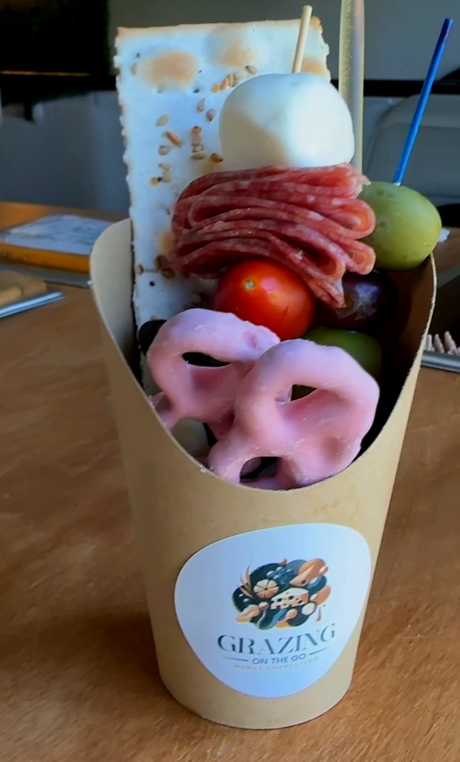 A cone-shaped container with various food items including sliced meat, vegetables, and a white ball, labeled 'GRAZING'.