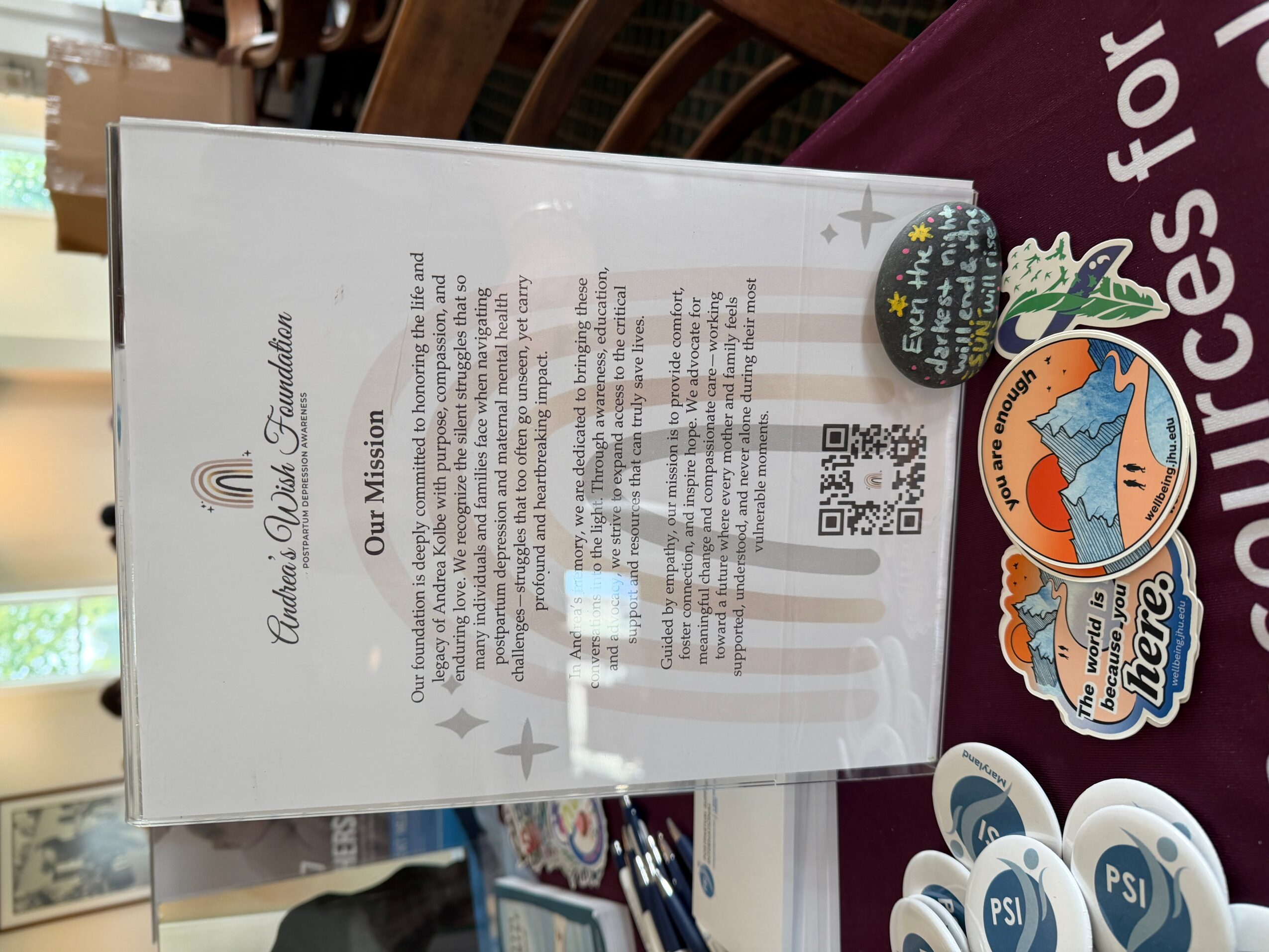 Menu board with text and QR code, placed on a table with stickers, in a restaurant setting.