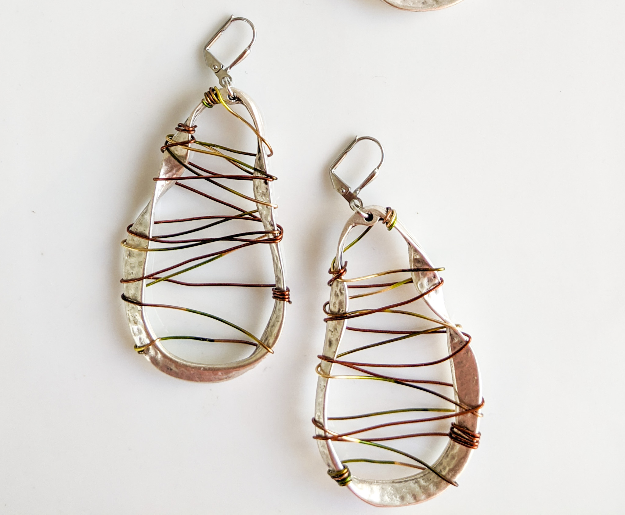 Pair of teardrop-shaped earrings with wire and bead design, on a white background.