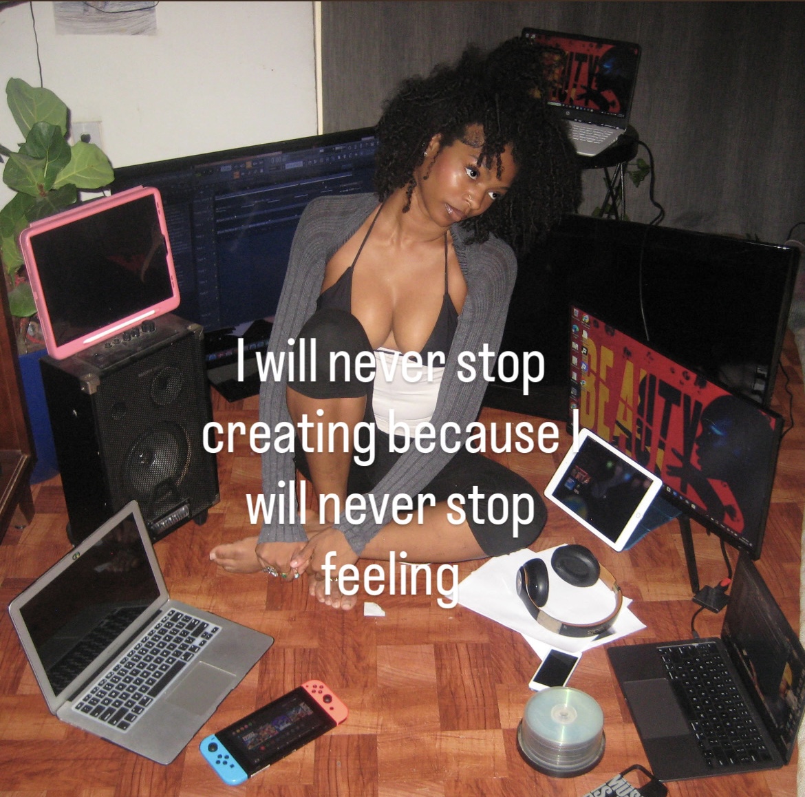 Woman with curly hair sitting at a desk with multiple electronic devices, including a laptop, monitor, and gaming console, with text overlay.