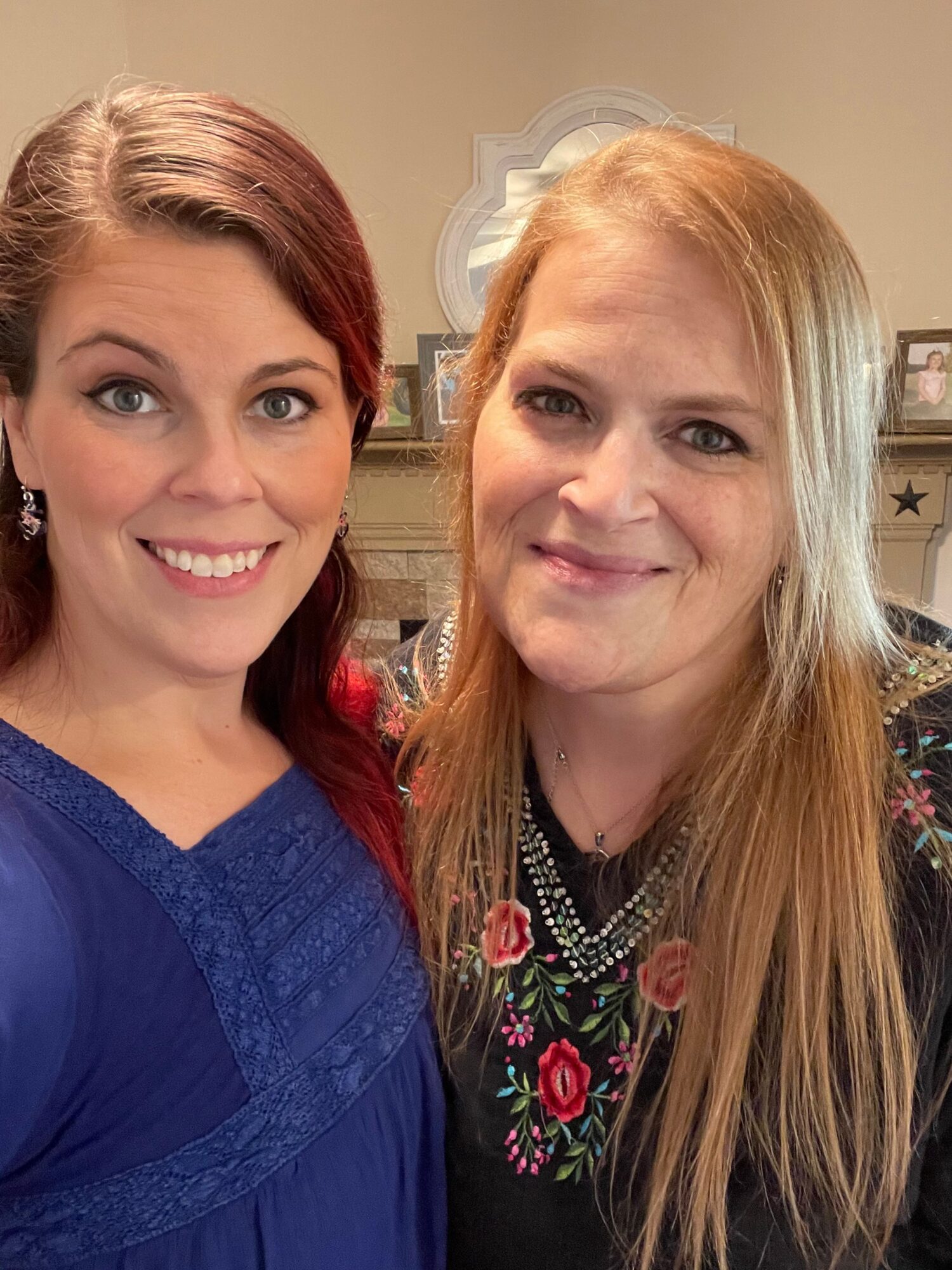 Two women smiling, one with blonde hair and the other with reddish-brown hair, in a close-up portrait.