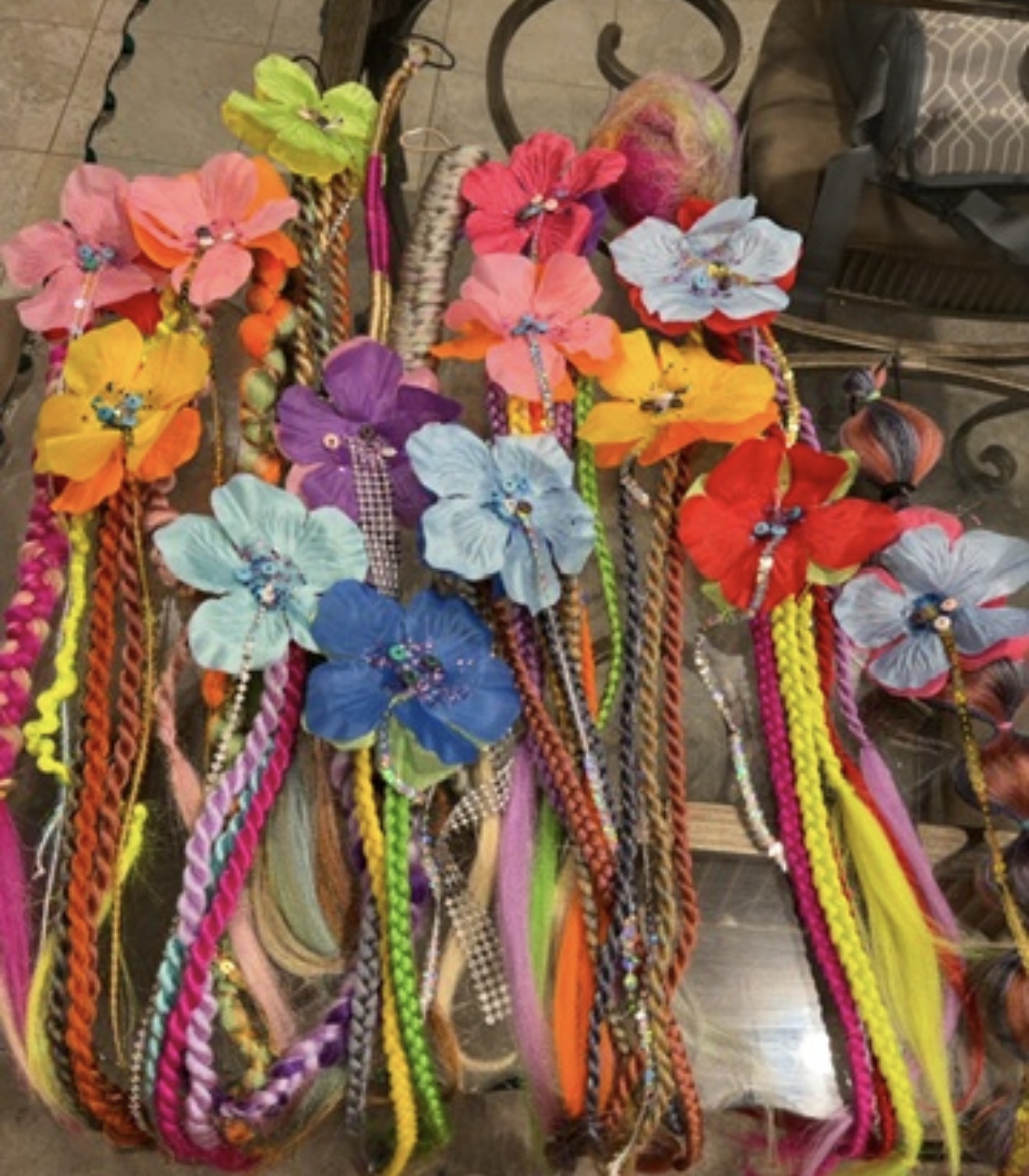 Colorful artificial flowers attached to long braided cords hanging from a display.