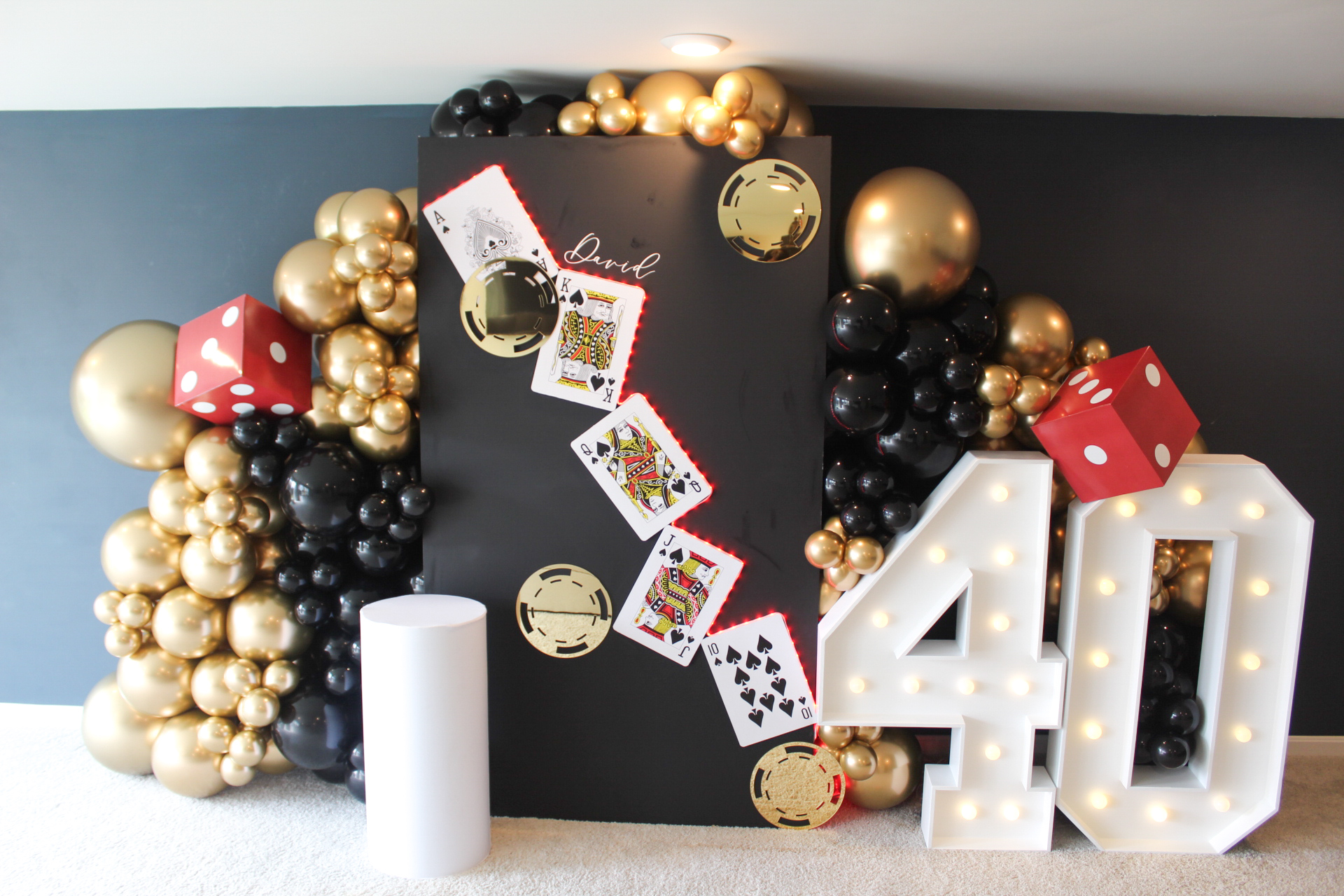 A black birthday display with gold and black balloons, playing cards, and illuminated number 40 decorations.