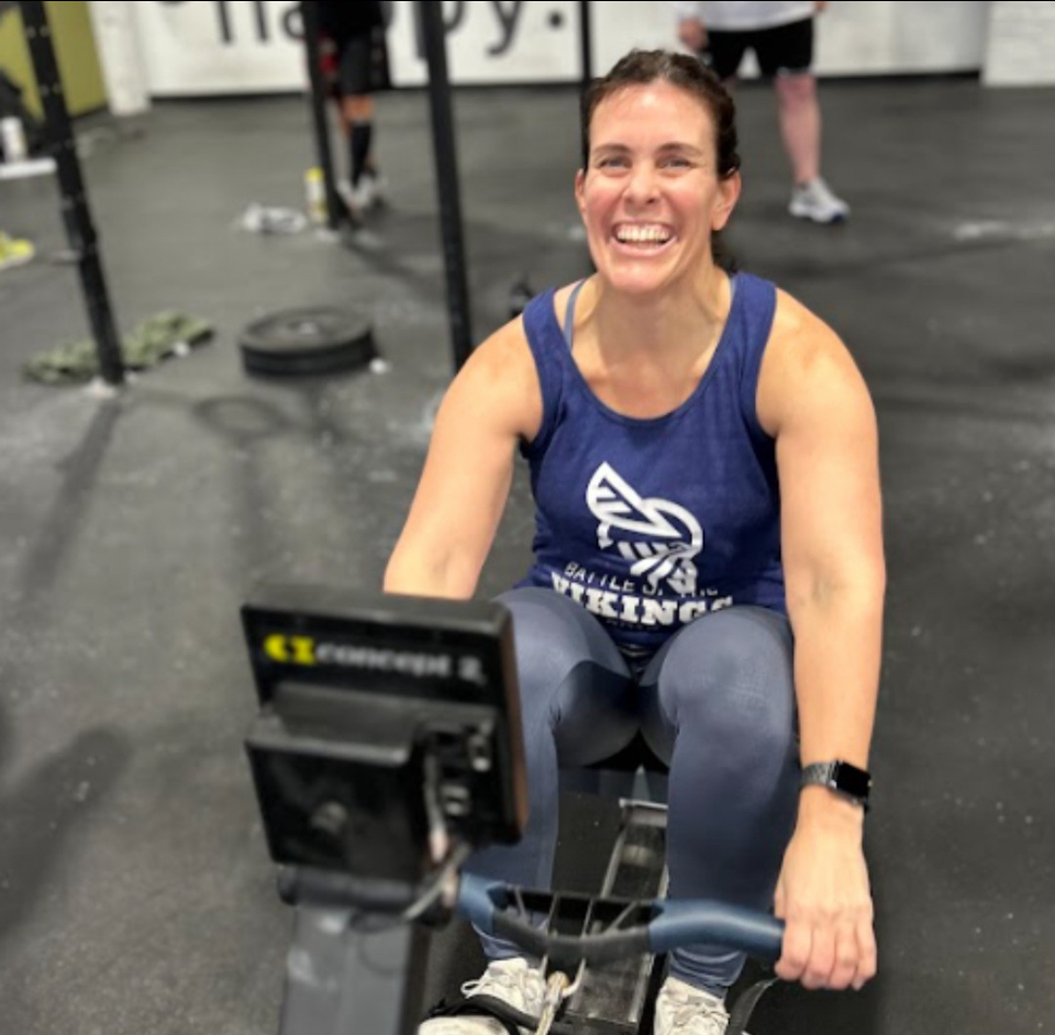 Person seated on an indoor exercise bike, holding the handlebars in a gym.