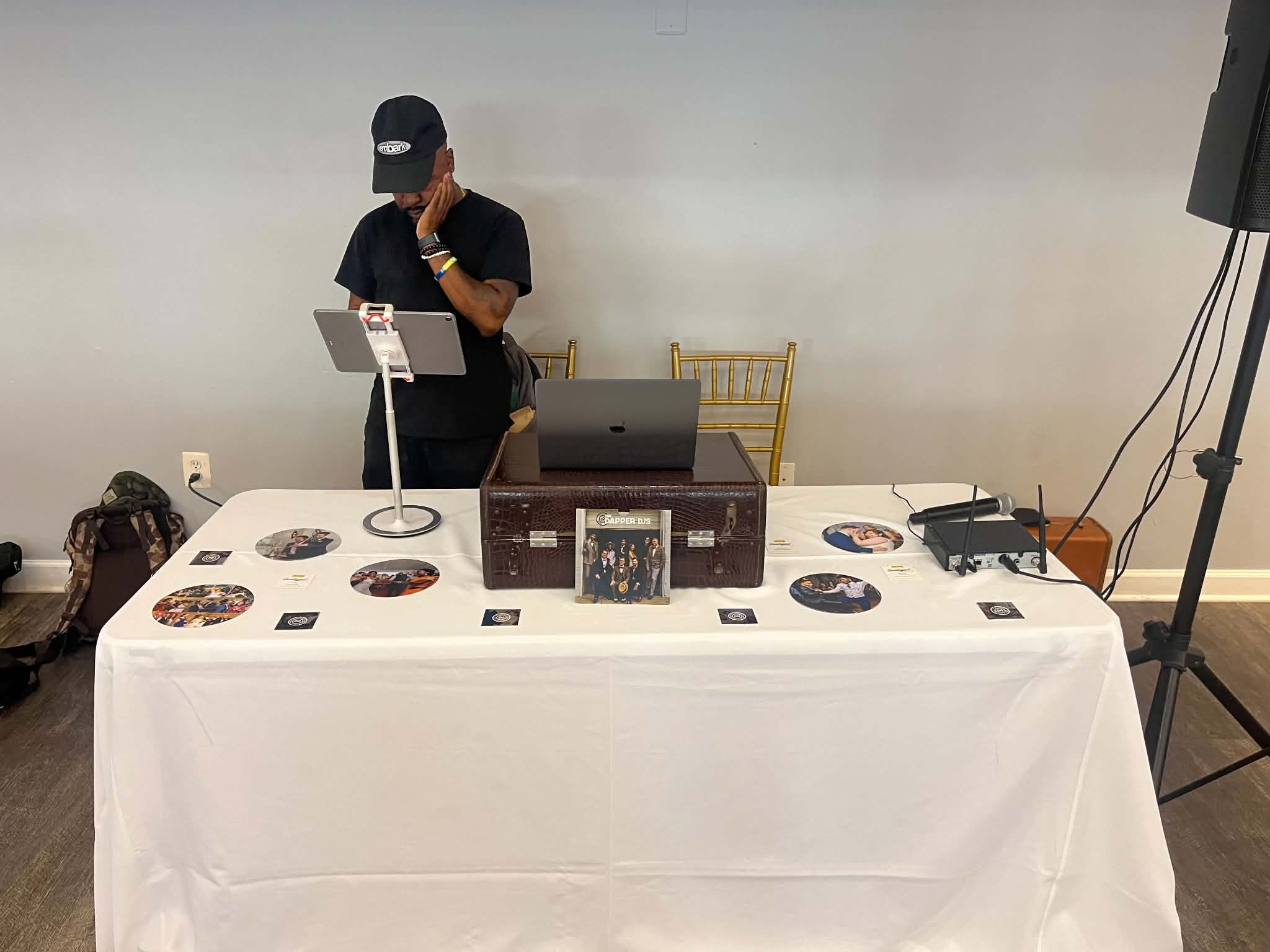 Person standing behind a table displaying records, audio equipment, and a laptop.