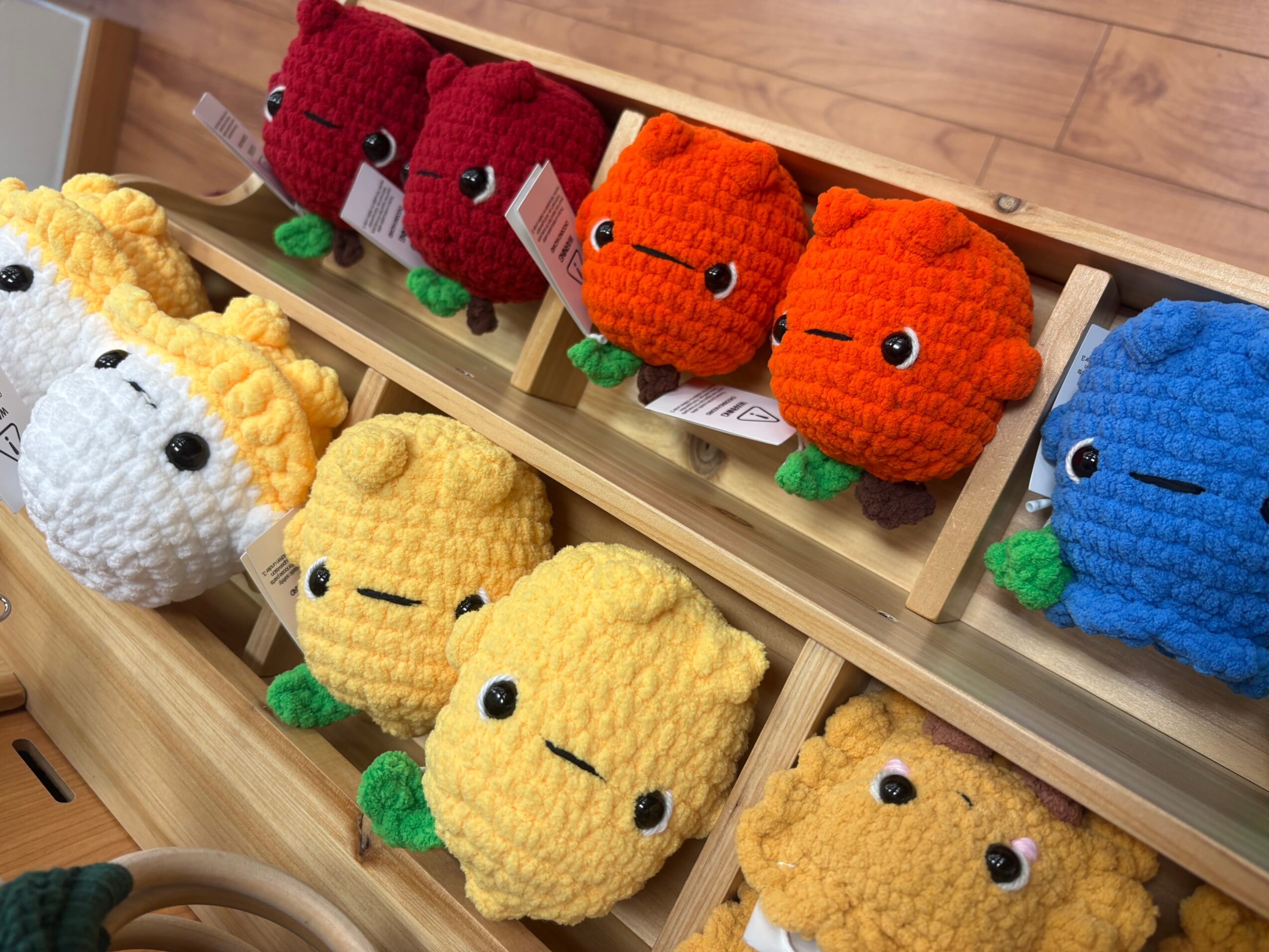 Rows of colorful crocheted animal toys displayed on wooden shelves.